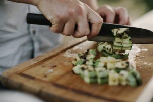 slicing vegetables with a knife on a cutting wooden board